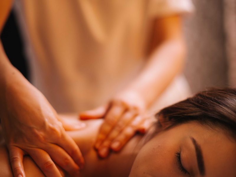 professional female hands giving doing back massage young brunette woman spa salon with soft lighting close up concept luxury professional massage concept body care min